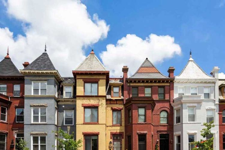 block of colorful DC rowhouses beneath azure sky
